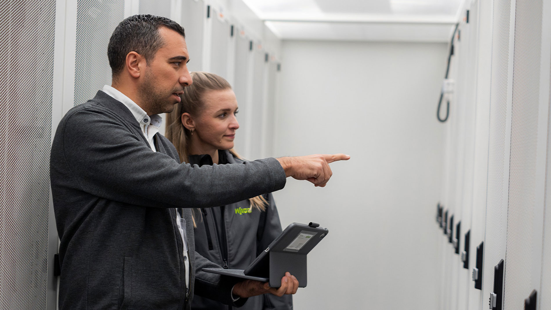 Fouad Boudraa, Business Developer, zeigt seiner Kollegin, Marketing Managerin Julia Skaszik (beide WAGO), im Serverraum eines Rechenzentrums, wie WAGO Technik die Kühlung energieeffizient optimiert. Bild: WAGO GmbH & Co. KG