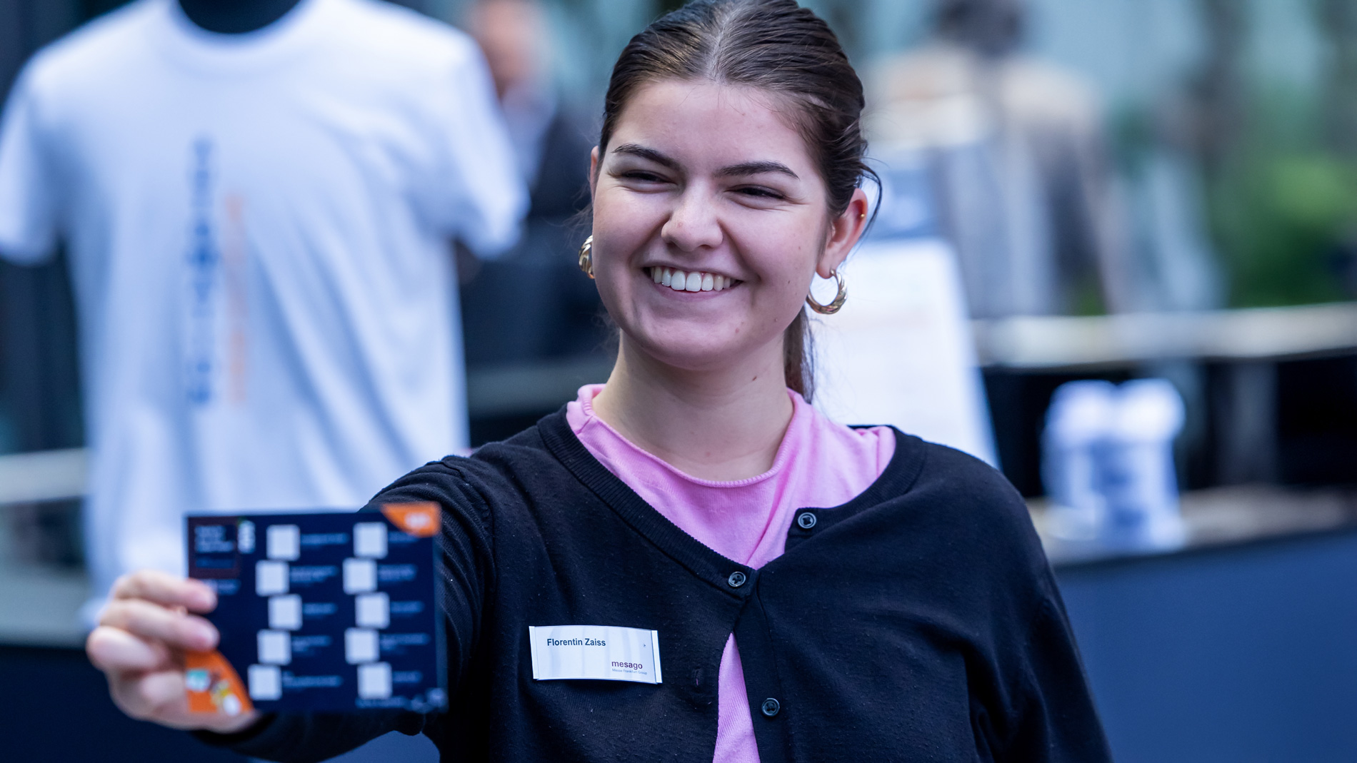 An SPS staff member hands out stamp cards for the Young Talents Rallye to young trade fair visitors.