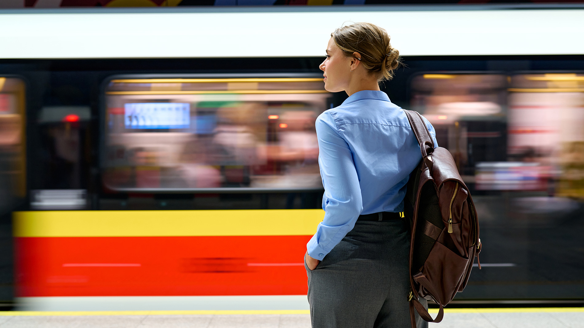Person standing on a railway platform in front of a moving train as a symbol of calculating CO₂ emissions for travel. Image: iStock.com / ValeriiApetroaiei
